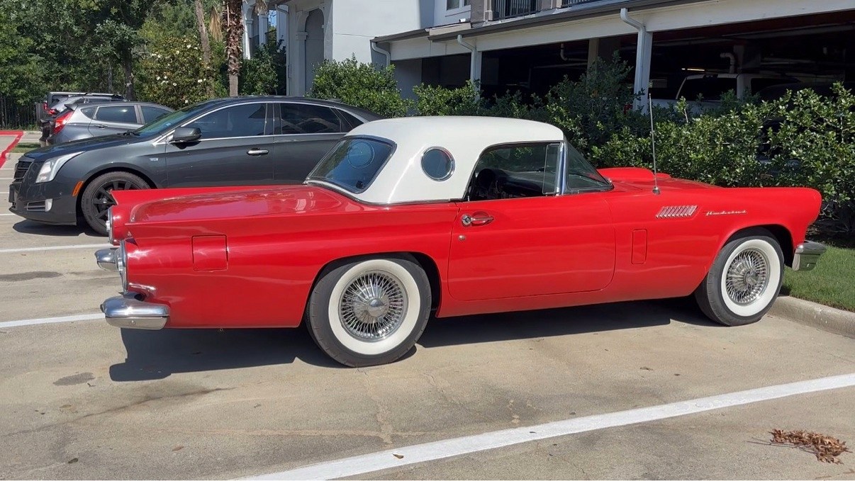 Red 1957 Ford Thunderbird in profile, white hardtop with porthole window and wide whitewall tires